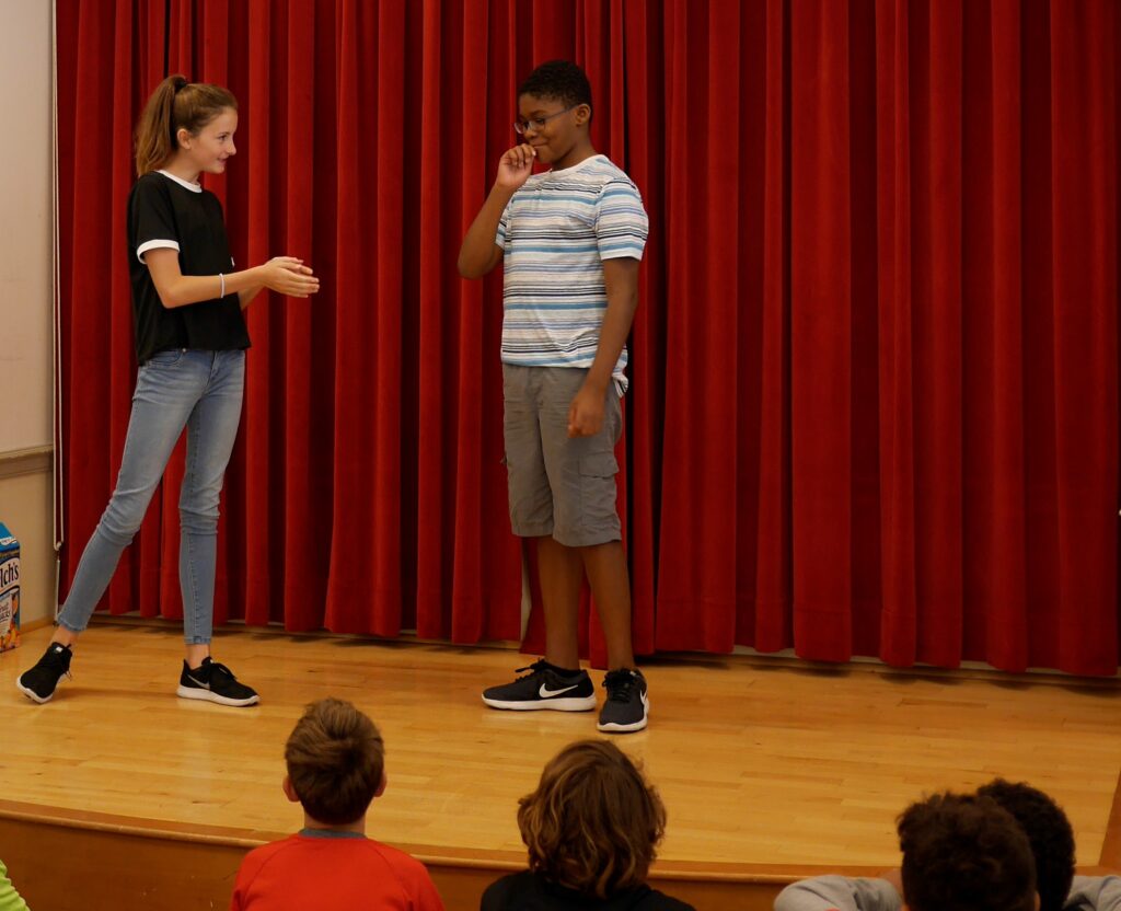 Two young actors doing improv on stage