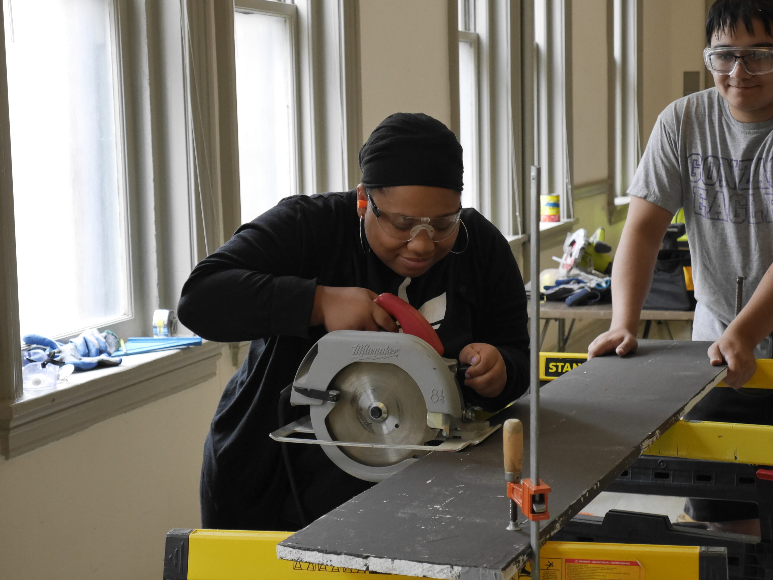 Student uses a circular saw on a clamped board